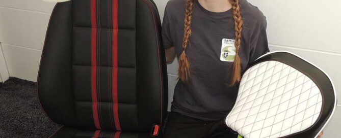 Junge Frau, die neben einem ausgebauten Autositz steht und selbst einen Autositz in der Hand hält.