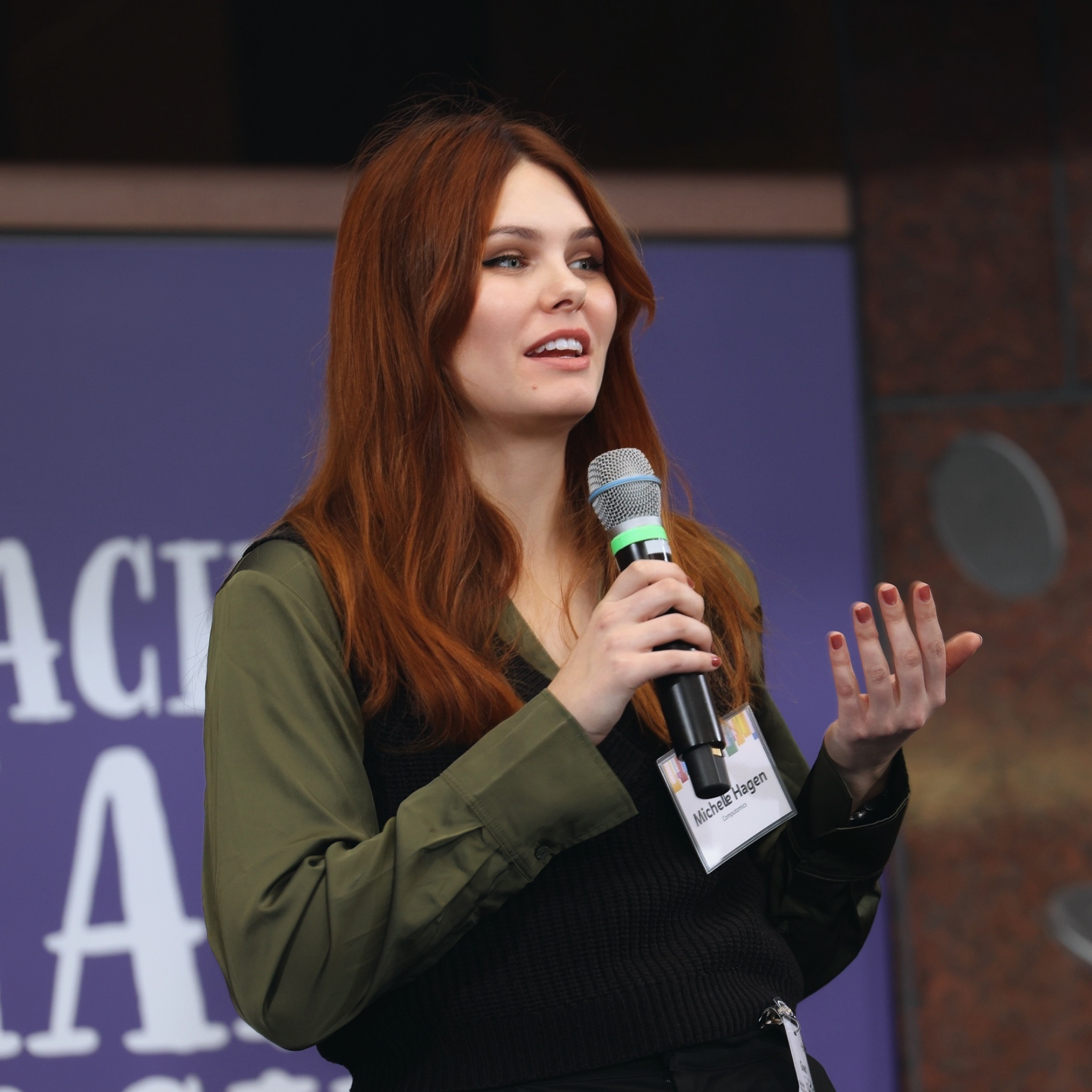 Eine junge Frau mit roten Haaren spricht in ein Micro.