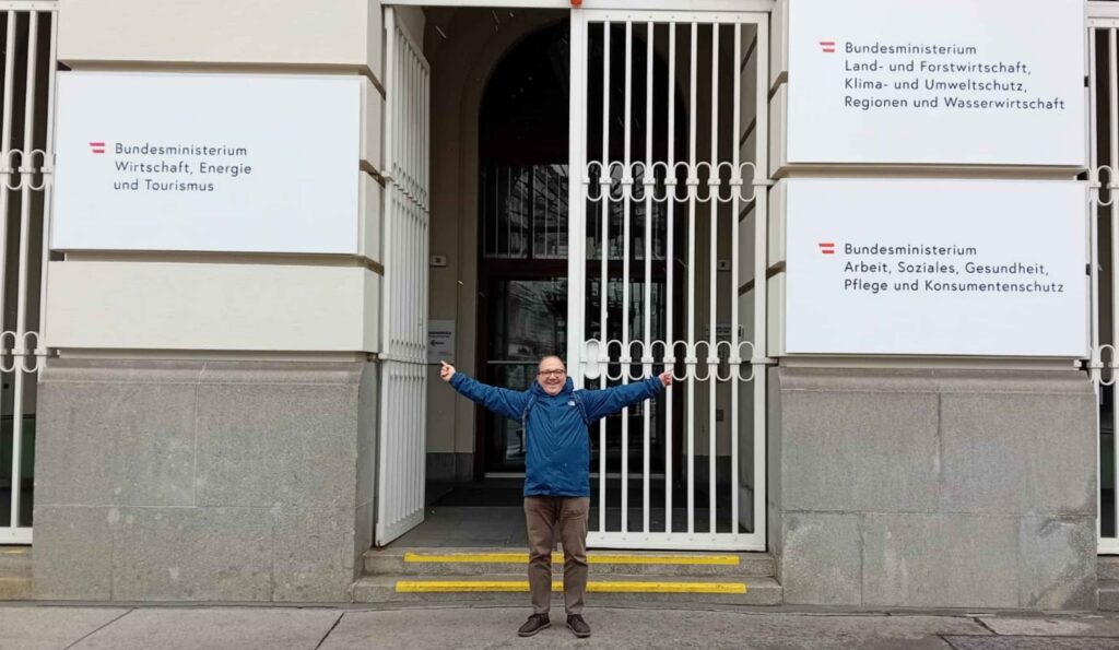 Design ohne Titel (5) Ein Mann mit ausgebreiteten Armen vor einem Regierungsgebäude