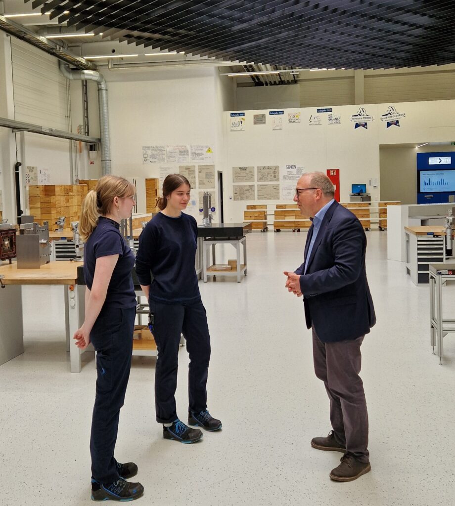 Starlim-1 Ein Mann und zwei junge Frauen im Gespräch in einer Werkstatt