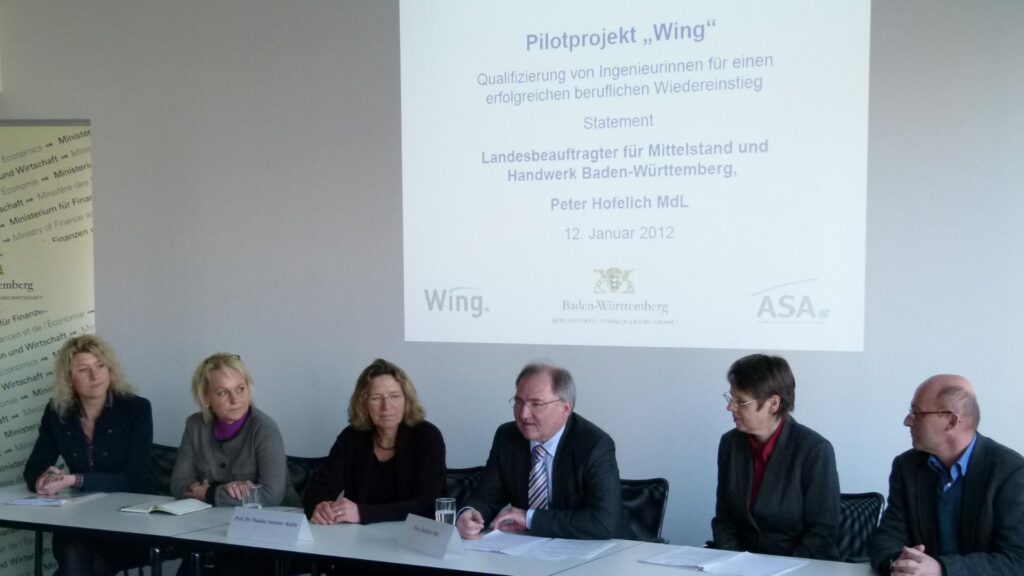 mint_blogbeitrag_jubiläum_bündmnis_1 (1) Vier Frauen und drei Männer an einem Konferenz-Tisch vor einer Leinwand